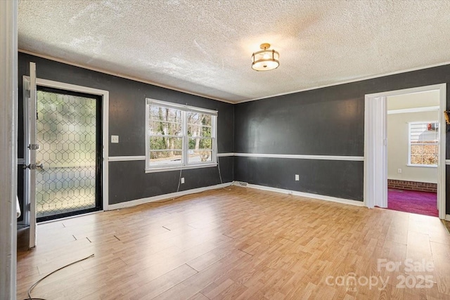 empty room featuring baseboards, a textured ceiling, and wood finished floors