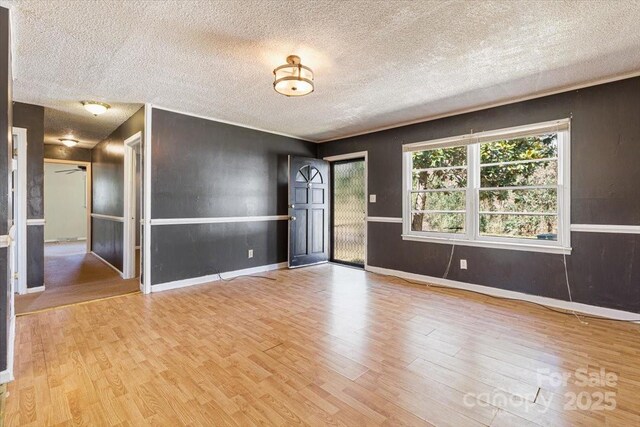 empty room featuring baseboards, a textured ceiling, and wood finished floors