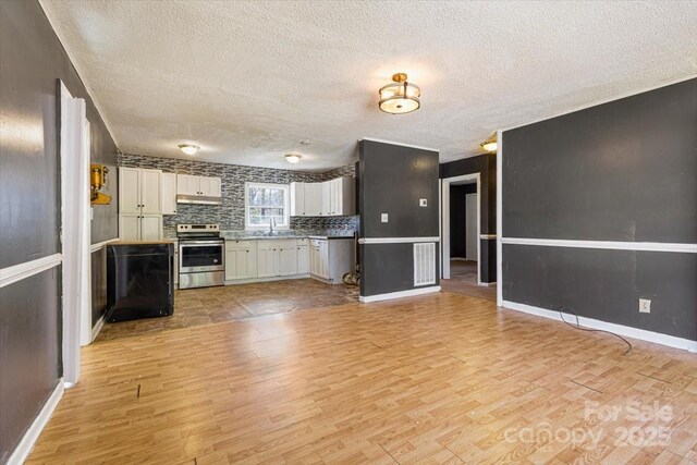 kitchen with a sink, stainless steel electric range oven, light wood-style floors, and decorative backsplash