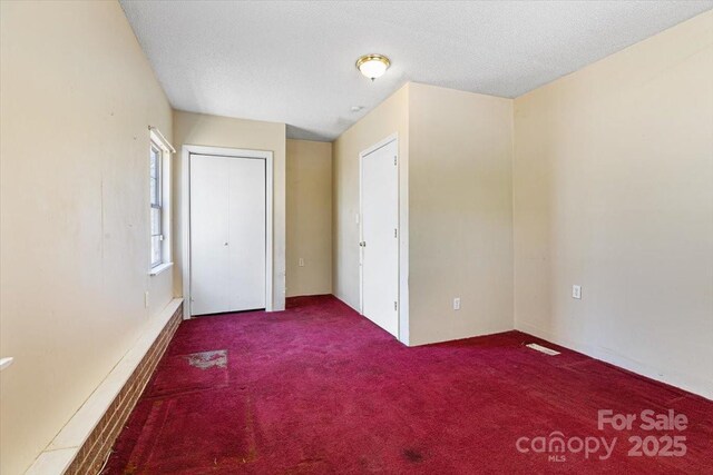 unfurnished bedroom featuring a textured ceiling and carpet floors