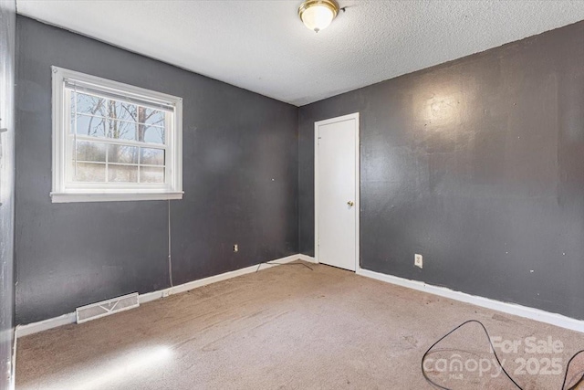 unfurnished room featuring carpet flooring, baseboards, visible vents, and a textured ceiling