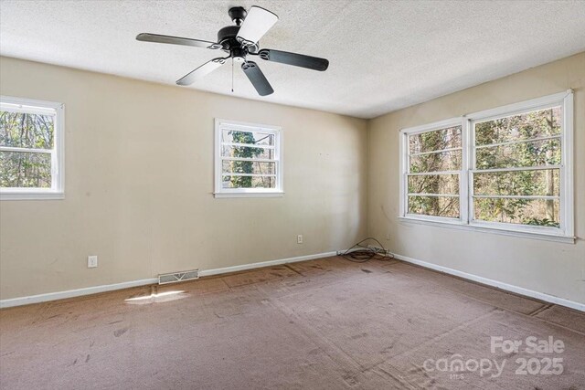 carpeted spare room featuring visible vents, a textured ceiling, and baseboards