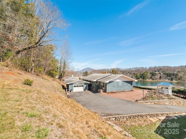 view of front of property with aphalt driveway, an attached garage, and a water view