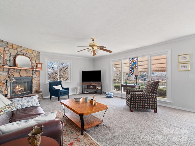 carpeted living room featuring a wealth of natural light, baseboards, a stone fireplace, and a textured ceiling