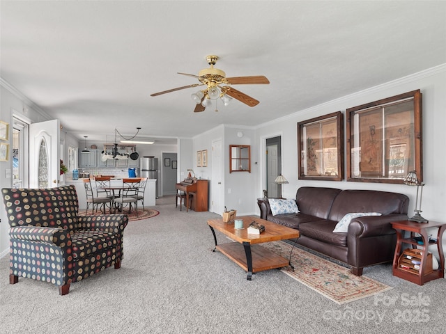 living area with ornamental molding, carpet flooring, and a ceiling fan