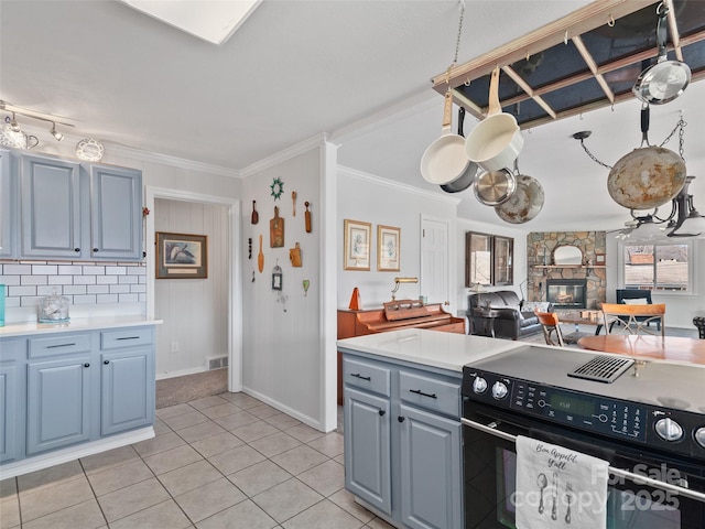 kitchen featuring ornamental molding, light countertops, a fireplace, and electric range