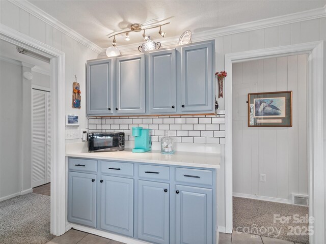 kitchen featuring light countertops, light carpet, crown molding, and backsplash