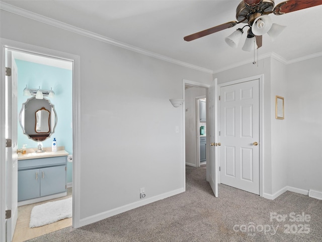 unfurnished bedroom featuring crown molding, carpet flooring, a sink, and baseboards