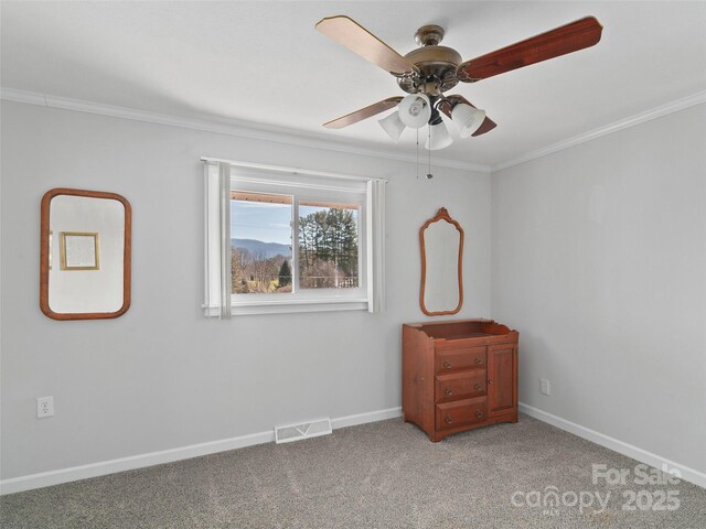 carpeted empty room with baseboards, visible vents, ceiling fan, and crown molding