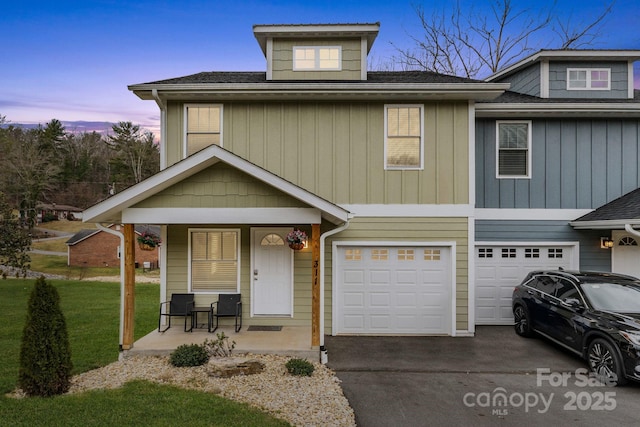 view of front of property with covered porch, driveway, roof with shingles, and an attached garage