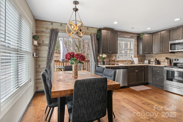 kitchen with recessed lighting, stainless steel appliances, dark brown cabinets, light countertops, and light wood finished floors