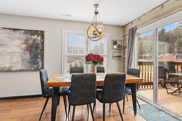 dining space with a wealth of natural light, light wood-type flooring, visible vents, and a notable chandelier