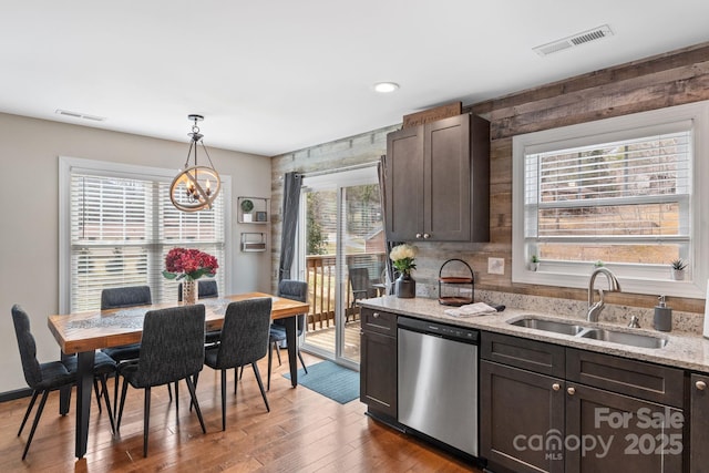 kitchen with dark brown cabinets, stainless steel dishwasher, a sink, and visible vents