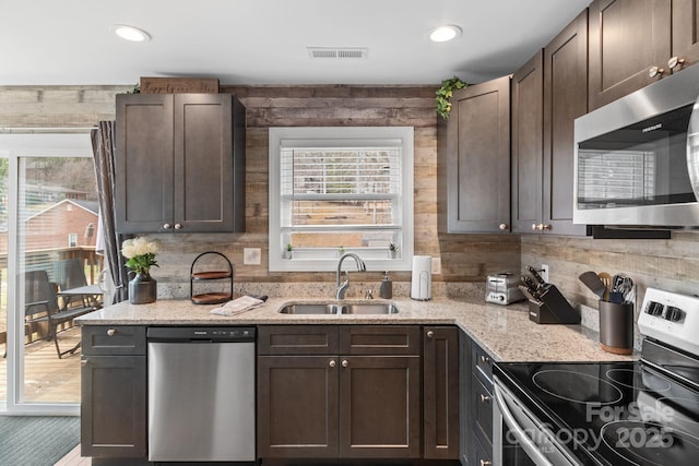 kitchen featuring stainless steel appliances, a sink, visible vents, dark brown cabinets, and backsplash