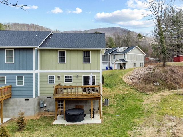 rear view of house with a deck with mountain view, central AC unit, a lawn, and a patio area