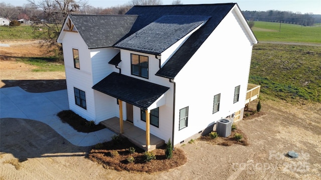 exterior space with cooling unit, driveway, and roof with shingles