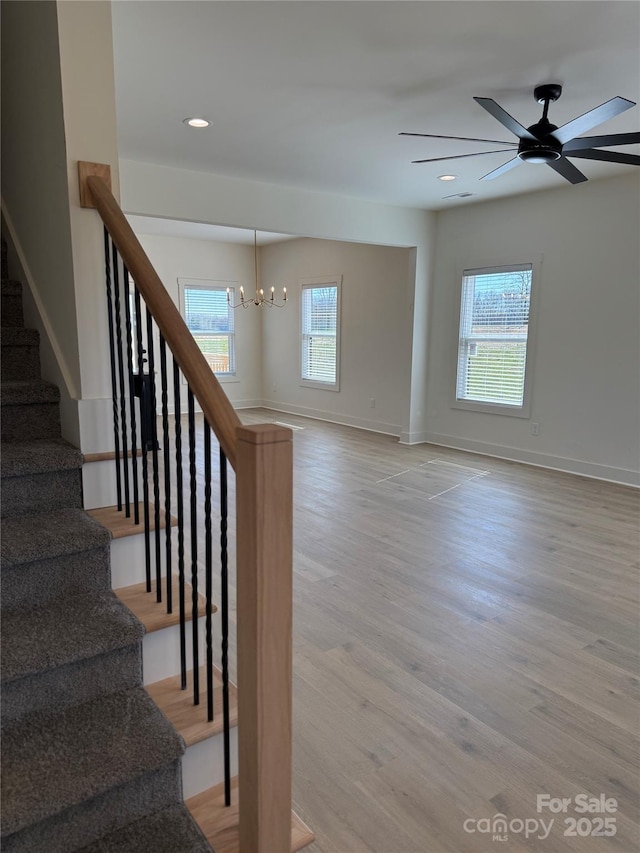 stairs featuring visible vents, ceiling fan with notable chandelier, wood finished floors, recessed lighting, and baseboards