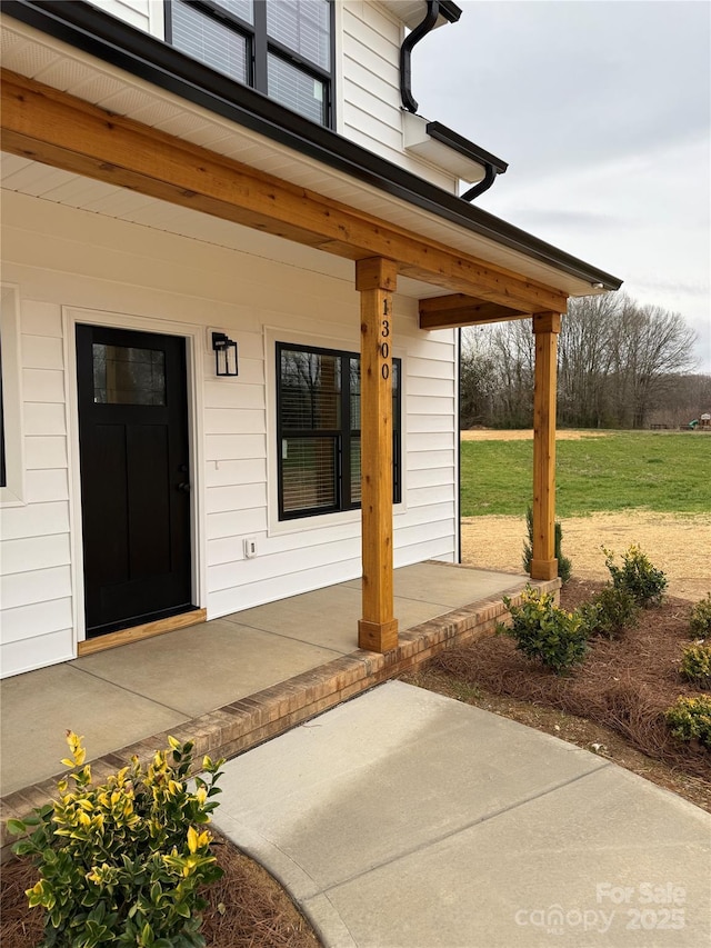 entrance to property with a yard and covered porch