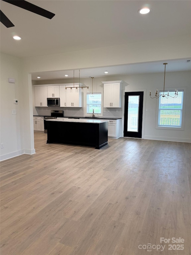 kitchen with hanging light fixtures, a healthy amount of sunlight, tasteful backsplash, and stainless steel appliances