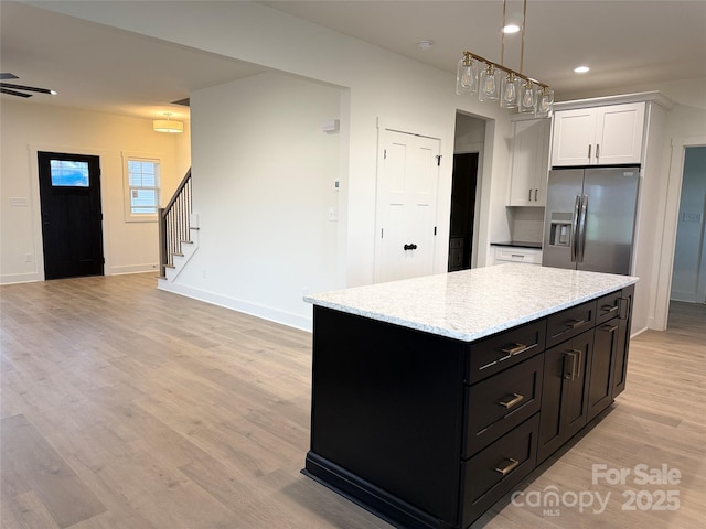 kitchen with a center island, light wood-style flooring, dark cabinetry, stainless steel refrigerator with ice dispenser, and white cabinetry