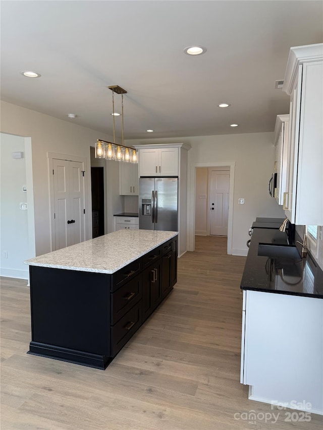 kitchen with a sink, a kitchen island, white cabinetry, stainless steel appliances, and light wood finished floors