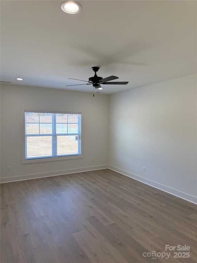 spare room featuring dark wood finished floors, recessed lighting, and baseboards