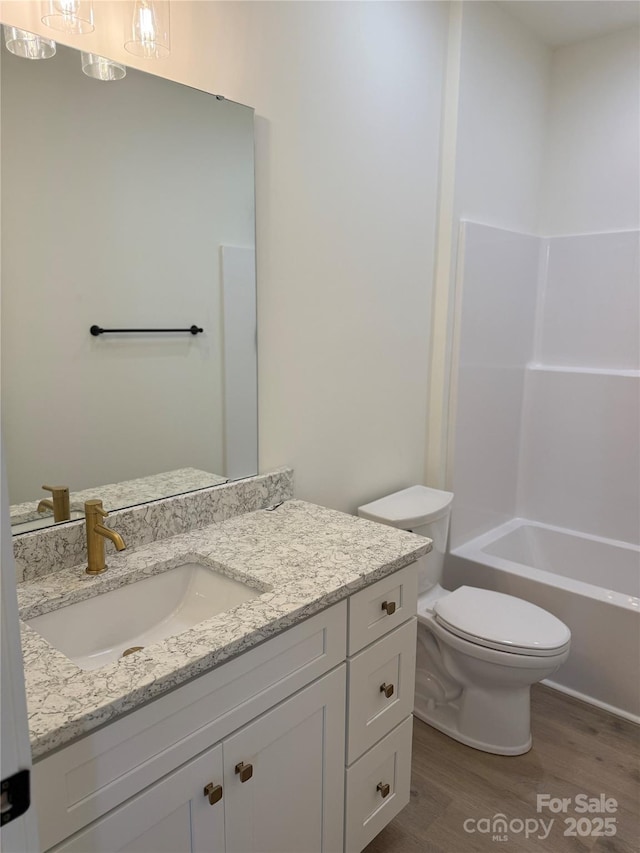 full bathroom featuring washtub / shower combination, toilet, wood finished floors, and vanity