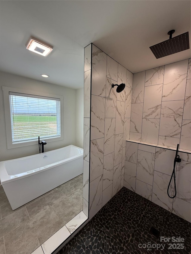 bathroom with a soaking tub and tiled shower