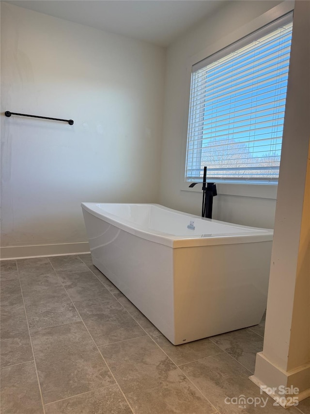 bathroom featuring baseboards and a freestanding bath