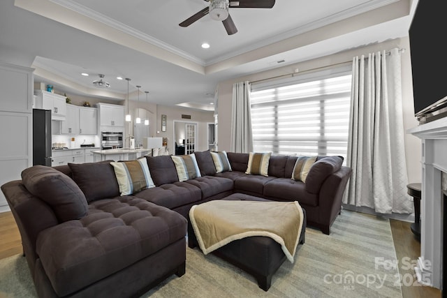 living area featuring ceiling fan, recessed lighting, light wood-type flooring, a raised ceiling, and crown molding