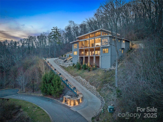 rear view of house featuring driveway and stucco siding