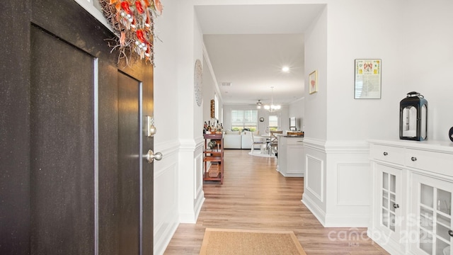 foyer with wainscoting, a decorative wall, and light wood finished floors