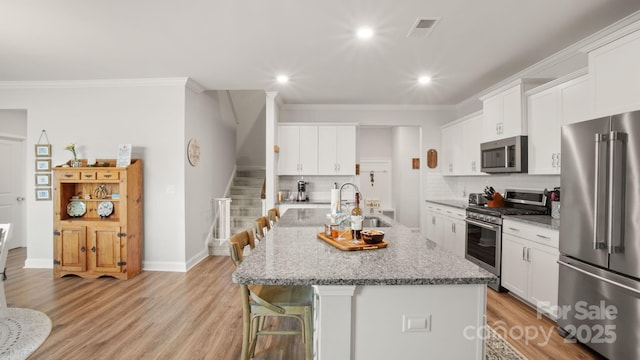 kitchen featuring light wood-style flooring, appliances with stainless steel finishes, a kitchen breakfast bar, and a sink