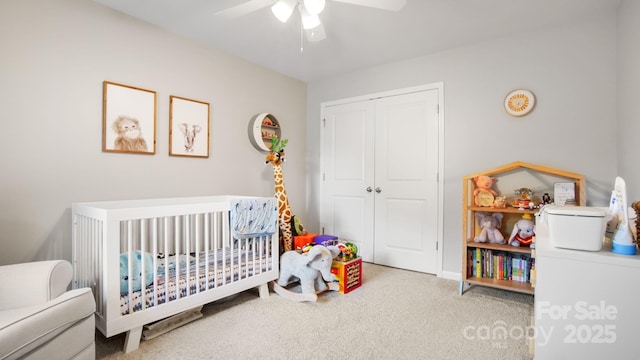 carpeted bedroom with a nursery area, ceiling fan, and a closet