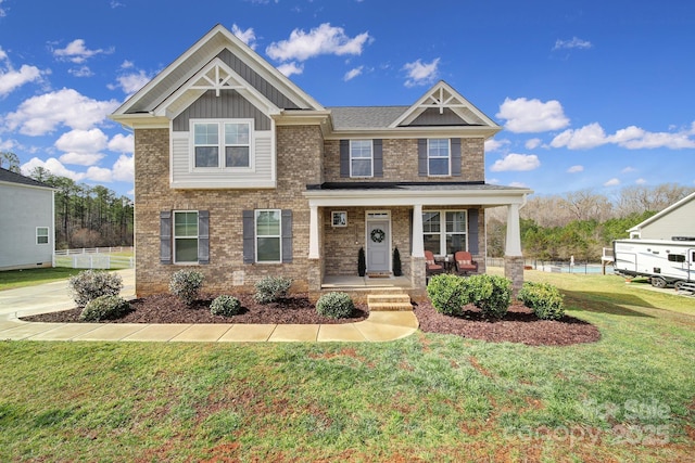 craftsman inspired home featuring covered porch, brick siding, board and batten siding, and a front yard