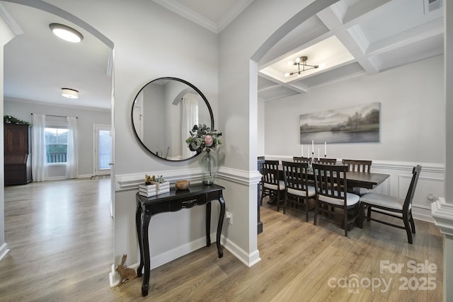 interior space featuring ornamental molding, coffered ceiling, wood finished floors, and beam ceiling