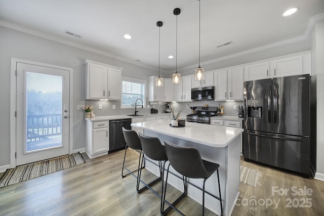 kitchen featuring stainless steel appliances, light countertops, visible vents, light wood-style floors, and white cabinets