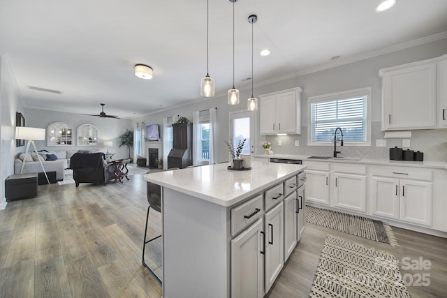 kitchen with a fireplace, a sink, backsplash, and light wood finished floors