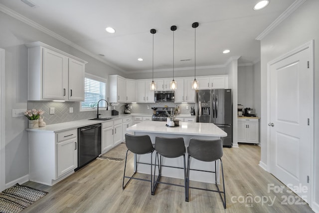 kitchen with stainless steel appliances, a sink, white cabinetry, and a kitchen breakfast bar