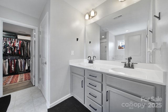 bathroom with double vanity, a spacious closet, a sink, and visible vents