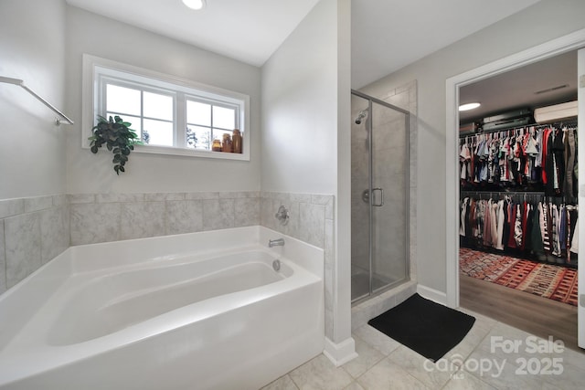 full bathroom with a stall shower, a walk in closet, a bath, and tile patterned floors