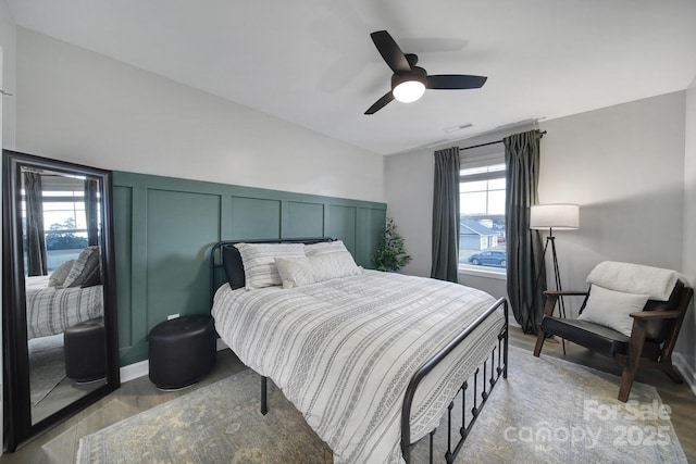 bedroom featuring light wood-type flooring, visible vents, a decorative wall, and a ceiling fan