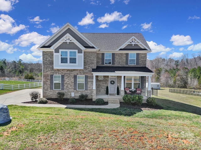 craftsman-style house featuring a front lawn, a porch, fence, and brick siding