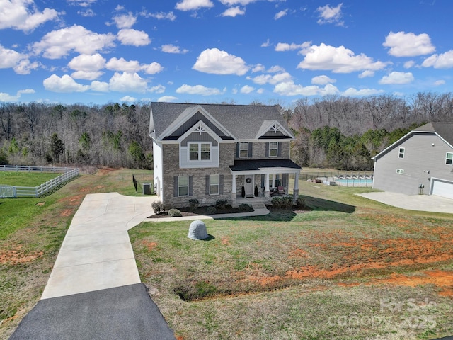 view of front of home with a forest view, fence, and a front lawn