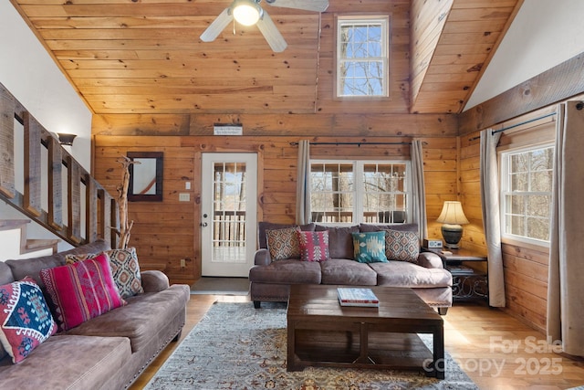 living room with wood walls, wooden ceiling, stairs, and wood finished floors