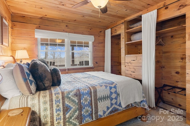 carpeted bedroom featuring ceiling fan, wooden walls, and wooden ceiling