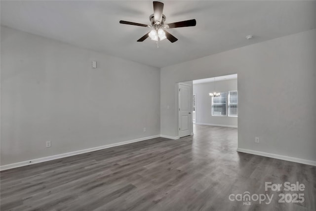 spare room featuring dark wood finished floors, baseboards, and ceiling fan with notable chandelier