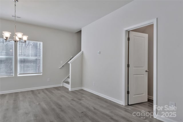 spare room with baseboards, visible vents, wood finished floors, stairs, and a chandelier