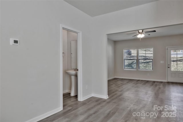 empty room featuring a ceiling fan, baseboards, and wood finished floors