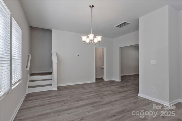 interior space featuring a notable chandelier, visible vents, stairway, wood finished floors, and baseboards